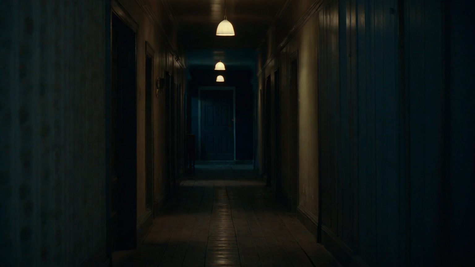 A dim hallway at night lit by one warm lamp against a cold window